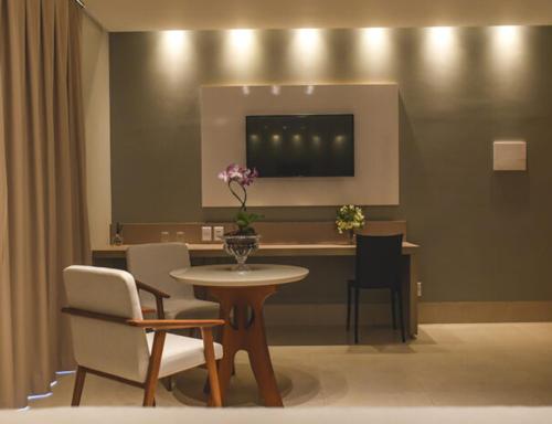 a dining room with a table and chairs and a table with flowers at Hotel D'Leon in Gurupi