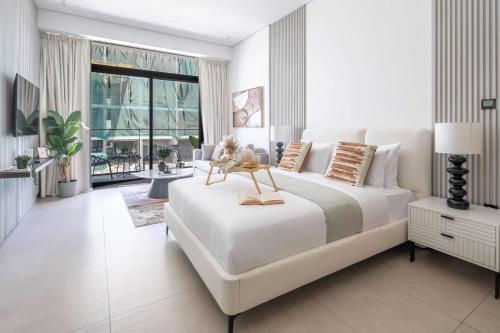 a white bedroom with a large white bed and a large window at Frank Porter - MYKA Residence in Dubai