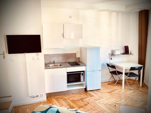 - une petite cuisine blanche avec un évier et une table dans l'établissement D Centre ville de Lyon et visite à pied, à Lyon