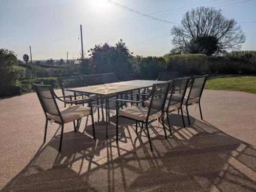 a wooden table and chairs with the sun behind it at Beautiful Victorian Farmhouse in Ottery Saint Mary