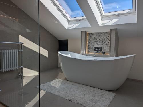 a bathroom with a large white tub and a skylight at Beautiful Victorian Farmhouse in Ottery Saint Mary