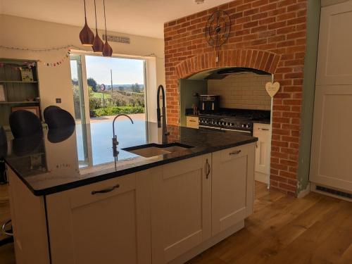 a kitchen with a counter and a brick wall at Beautiful Victorian Farmhouse in Ottery Saint Mary