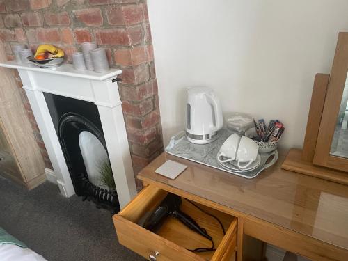a room with a fireplace with a coffee maker on a table at Camaraderie Guest House in York