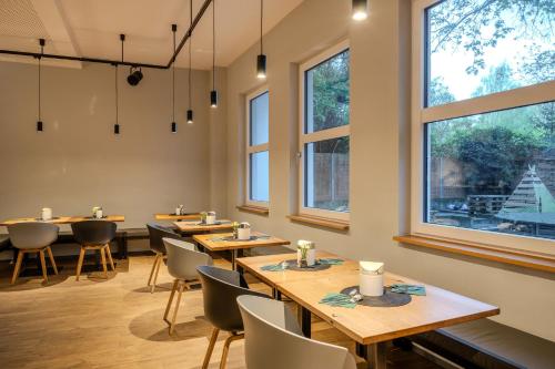 a restaurant with wooden tables and chairs and windows at mk hotel berlin in Berlin