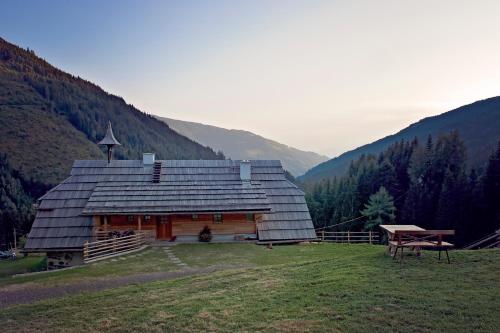a large wooden cabin in the mountains with a picnic table at Sandrisser-Hütte in Innerkrems