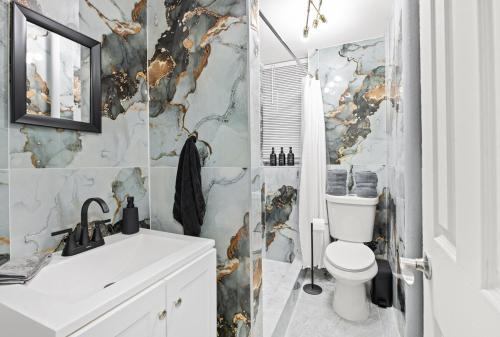 a bathroom with a white toilet and a marble wall at Modern 3BR Stay - Up to 7 Guests - 20 Mins to NYC in West New York