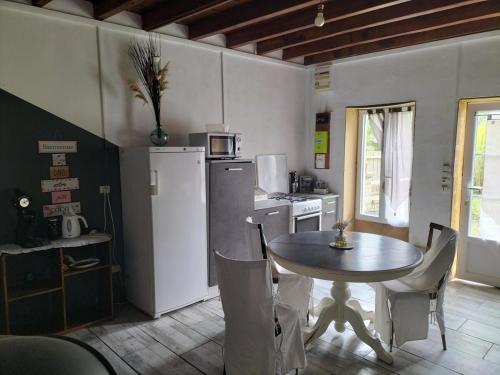 une cuisine avec une table et un réfrigérateur dans l'établissement Studio in all its simplicity, à Le Bourdet