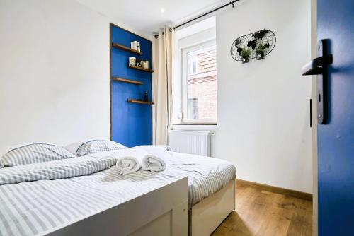 une chambre avec un lit aux murs bleus et une fenêtre dans l'établissement Maison du Vieux lille - moderne et authentique, à Lille