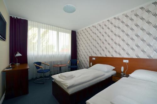 a hotel room with two beds and a table and chairs at Arkada Hotel in Bučovice