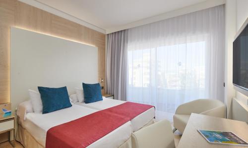a hotel room with a large bed with blue pillows at Grupotel Acapulco Playa - Adults Only in Playa de Palma