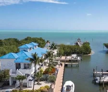a house with a dock and a boat in the water at Luxurious 2BR 2BA Ocean Pointe Condo Tavernier Fl in Tavernier