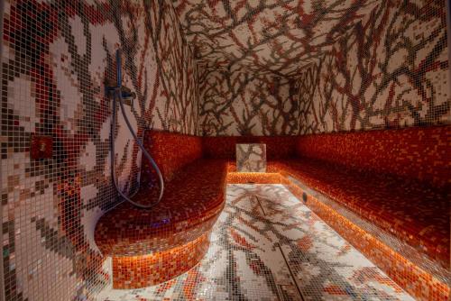 a bathroom with a toilet and a mosaic wall at Nuvole Garden Hotel in Brunate