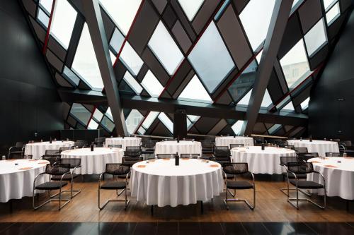 a room with white tables and chairs and windows at SO/ Vienna in Vienna