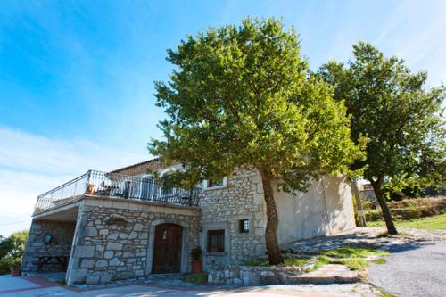 une maison en pierre avec un balcon et un arbre dans l'établissement Le Coccole, à Guardiaregia