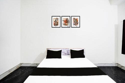 a bed in a white room with three pictures on the wall at SPOT ON JAYDEVI SEVA SADAN in Mathura