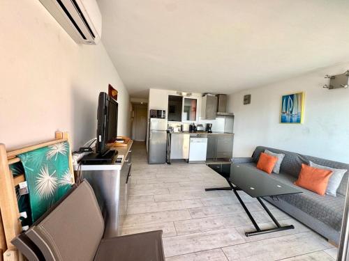un salon avec un canapé et une cuisine dans l'établissement T2 Poulen, climatise vue mer , parking inclus NON FUMEUR, à La Ciotat
