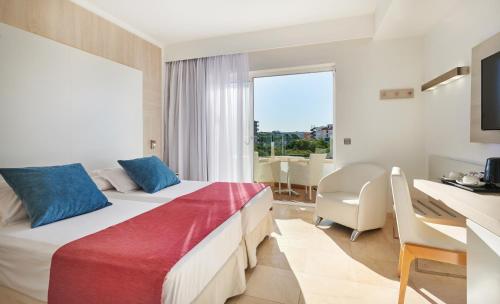 a hotel room with a bed and a desk and a window at Grupotel Acapulco Playa - Adults Only in Playa de Palma