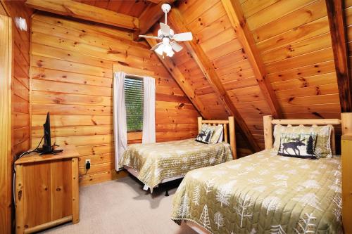 a bedroom with two beds in a log cabin at 1BR2 bath log cabin sleeps 6- walk to Titanic Museum and 5 miles from Dollywood! in Pigeon Forge