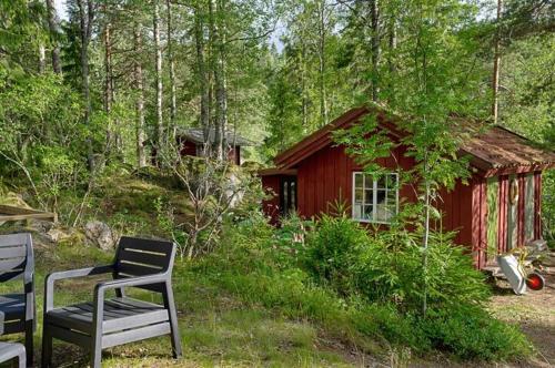 a red cabin with two chairs in front of it at Rent your own island! in Lersjötorp