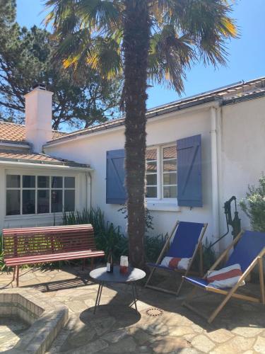 une maison avec un palmier, deux chaises et une table dans l'établissement Grande maison de vacances avec piscine, à La Guérinière