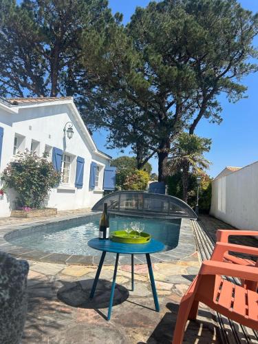 - une terrasse avec une table et une bouteille de vin dans l'établissement Grande maison de vacances avec piscine, à La Guérinière