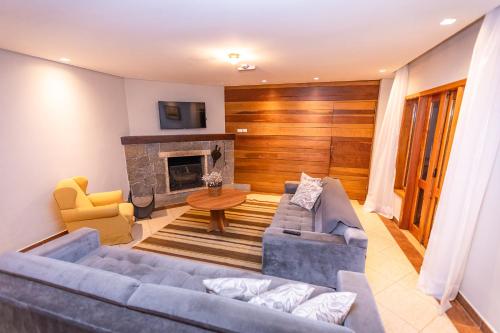 un salon avec un canapé et une cheminée dans l'établissement Villa Hegus no Alto da Boa Vista, à Campos do Jordão