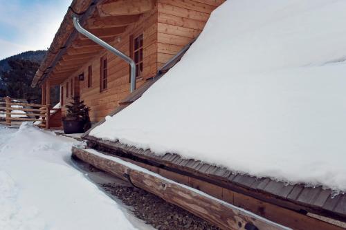 a log cabin with snow on the side of it at Sandrisser-Hütte in Innerkrems