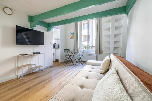 un salon avec un canapé et une télévision dans l'établissement LE PETIT PALAIS avec mezzanine de charme au cœur de Cannes, à Cannes