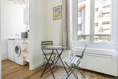 d'une petite table et de deux chaises dans une cuisine avec une fenêtre. dans l'établissement LE PETIT PALAIS avec mezzanine de charme au cœur de Cannes, à Cannes