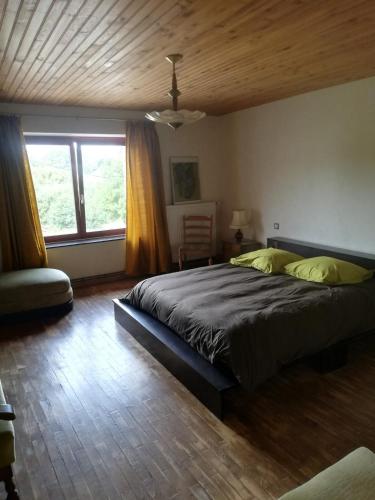 une chambre avec un grand lit et une fenêtre dans l'établissement Le 115, retour aux sources, à Hadol