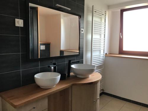 La salle de bains est pourvue de 2 lavabos blancs sur un comptoir en bois. dans l'établissement Le 115, retour aux sources, à Hadol
