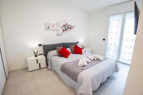 a white bedroom with a bed with red pillows at Le Ninfee in Zola Predosa