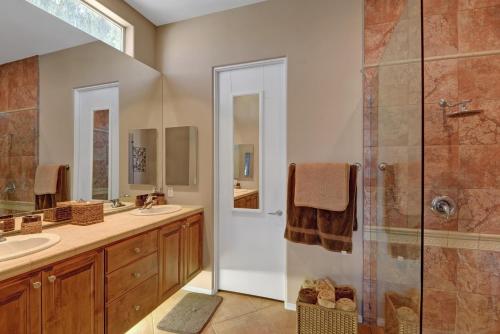 Un baño con dos lavabos y una ducha. en Hidden Jewel, en Cathedral City
