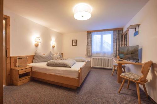 a bedroom with a bed and a desk and a television at Die Schlickeralm in Telfes im Stubai