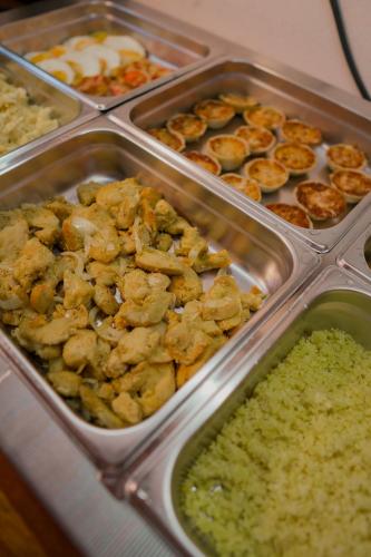 a buffet of food in metal trays on a table at Xamã Senses - Hotel Pousada in Pipa