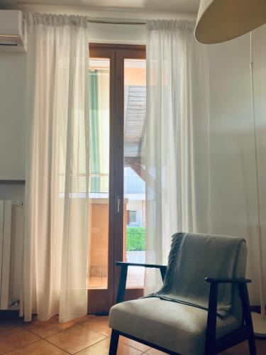 a living room with a chair and a sliding glass door at Casa Davide in Castelnuovo del Garda