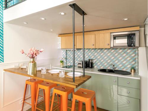 une cuisine avec des chaises orange et un comptoir en bois dans l'établissement Merveil - Luxury Suite - Champs Elysées - Mermoz, à Paris