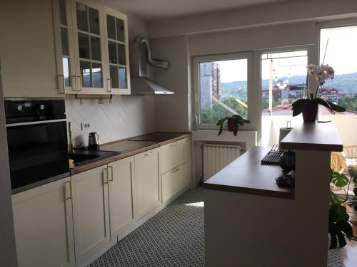 eine Küche mit weißen Schränken und einem großen Fenster in der Unterkunft Dijuto Apartment in Skopje