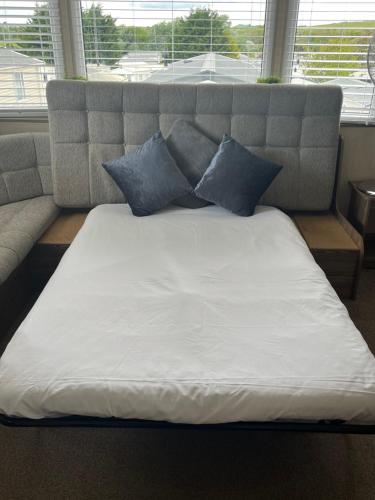 a bed with blue pillows on top of it at Combe Haven in Hastings