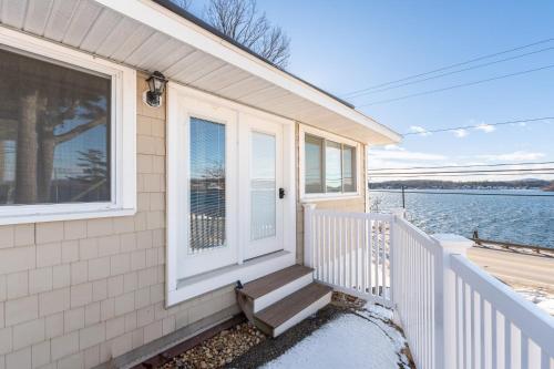 a house with a white door and stairs next to the water at Steps to Beach Lake-View Laconia Getaway! in Laconia