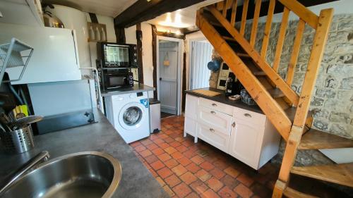 a kitchen with a washer and a sink and a staircase at La Longère d'Auberville in Auberville