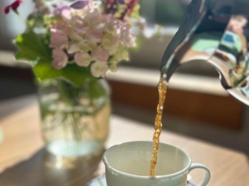 a person pouring coffee into a cup with a vase of flowers at Finkenhof - Haus Meersmannufer in Hannover