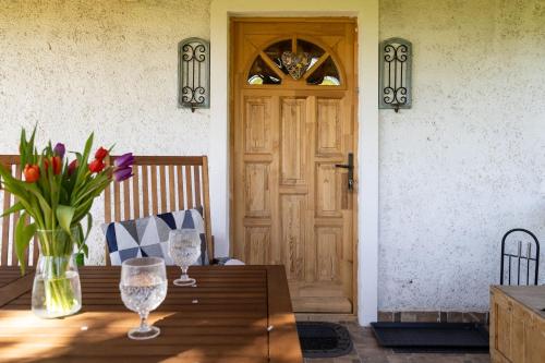 a table with a vase of flowers and a door at Balatoni Présházikó in Szőlősgyörök