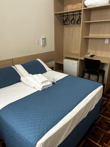 a bedroom with a blue and white bed and a desk at BARLOS HOTEL in Uruguaiana