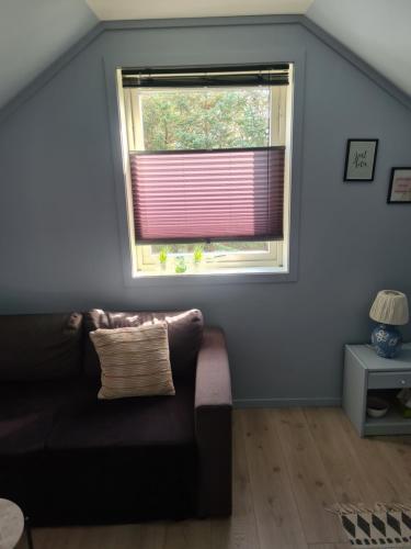 a living room with a couch and a window at Rom med privat bad, gratis parkering og Wifi in Vormedal