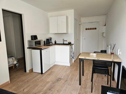 une petite cuisine avec une table et un micro-ondes dans l'établissement Le Fortitude - Omaha Beach, à Colleville-sur-Mer