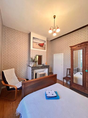 une chambre avec un lit, une chaise et un miroir dans l'établissement La Maison de Charles, à Montauban