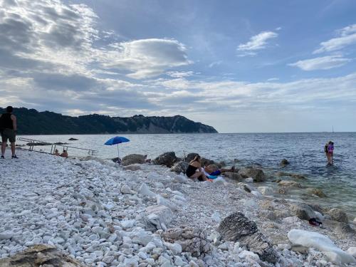 a group of people sitting on a rocky beach at Il Belvedere sul Conero in Potenza Picena