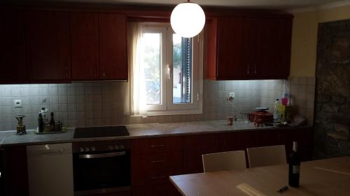 a kitchen with brown cabinets and a window and a table at Big Two-Storey House up to 8 person in Ayía Sofía