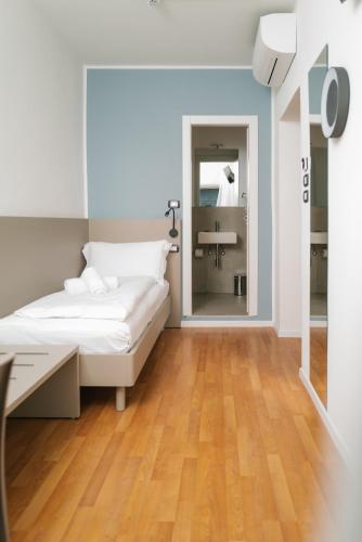 a white bedroom with a bed and a mirror at Ventus Park Hotel in Nago-Torbole